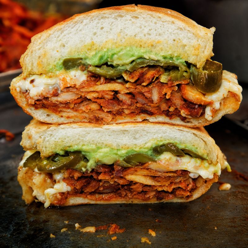 Torta al pastor cross-section with avocado and pickled jalapeno